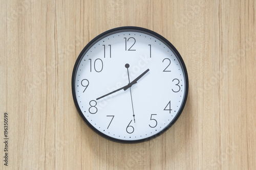black and white clock hangs on wooden wall