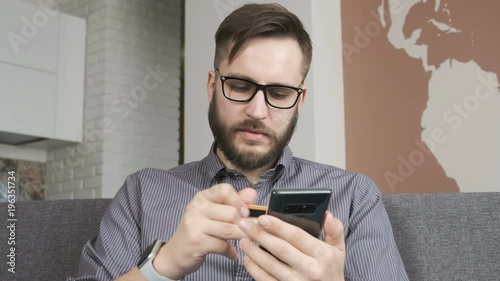 One businessman sit in office hold visa bankcard and typing at telephone touch screen for currency pay in on line store. The financial bussinessperson in workplace purchasing. Commercial concept photo