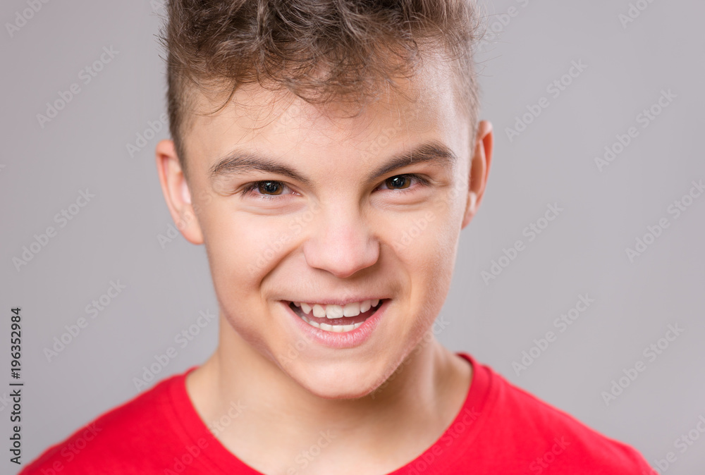 Close up emotional portrait of caucasian teen boy. Handsome smiling guy. Funny cut teenager on gray background. Child looking away. Close up emotional portrait of caucasian teen boy. Handsome smiling guy. Funny cut teenager on gray background. Child looking away.