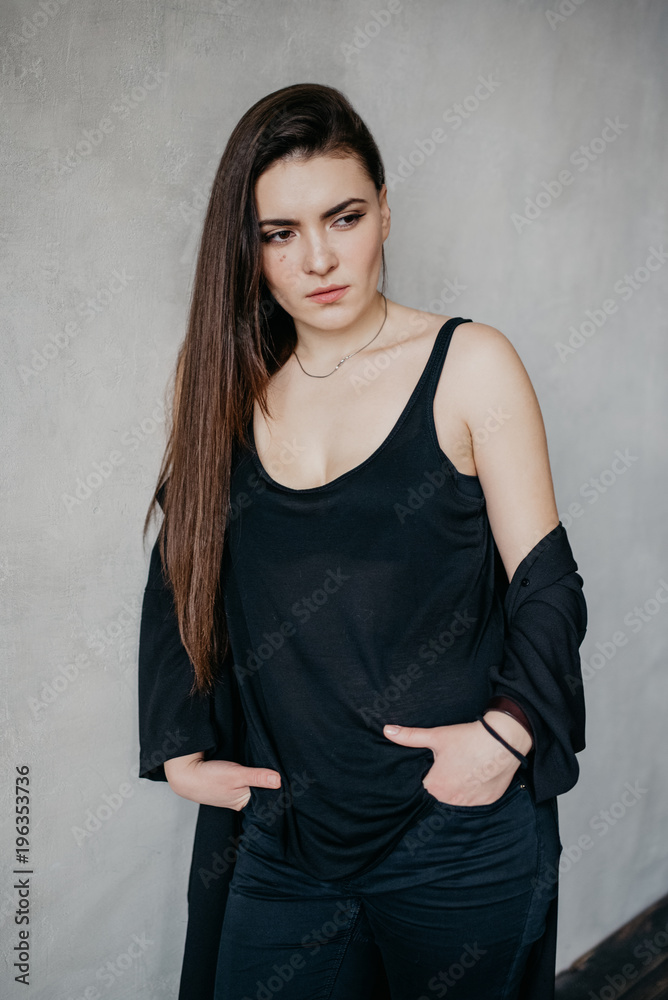 Hipster beautiful girl wearing black clothes posing against gray wall. Portrait of attractive girl in profile. Hipster beautiful girl wearing black clothes posing against gray wall. Portrait of attractive girl in profile.