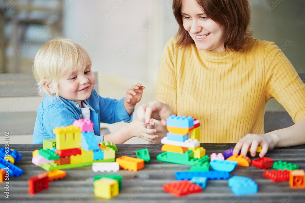 Mother playing colorful construction blocks with her son Mother playing colorful construction blocks with her son