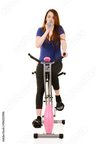woman drinking water during cardio on an exercise bike
