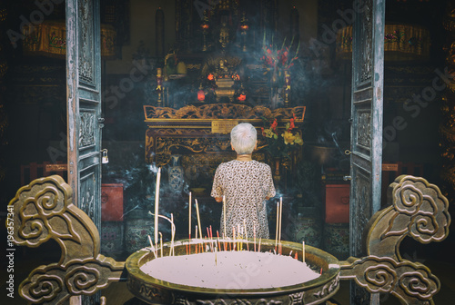 Senior woman praying buddha at temple