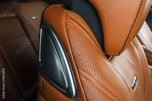 Modern Luxury car inside. Interior of prestige modern car. Comfortable leather red seats. Orange perforated leather. Modern car interior details