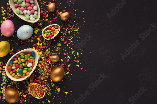 Colorful easter eggs and sprinkles on black background