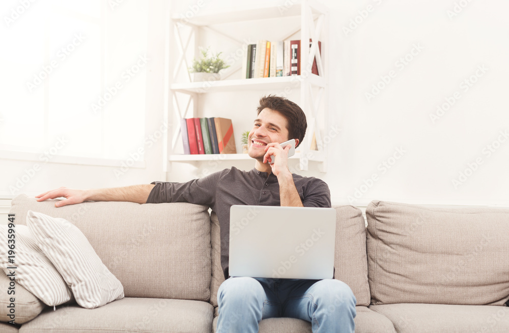 Smiling young man at home with laptop and mobile Smiling young man at home with laptop and mobile