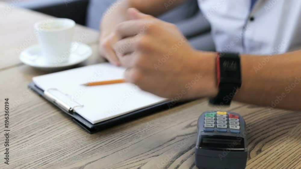 The young man is paying with a smart watch in a cafe The young man is paying with a smart watch in a cafe