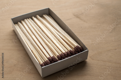Long wooden safety matchsticks stacked in cardboard matchbox on wooden background