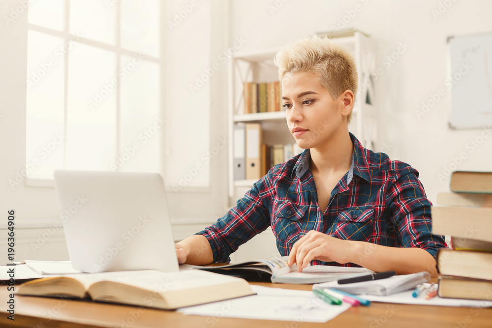 Student girl studying at table full of books Student girl studying at table full of books