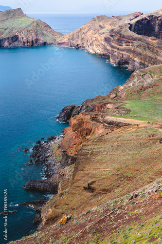 Beautiful blue bay surrounded by rocky cliffs during the sunny day in Madeira island, Portugal