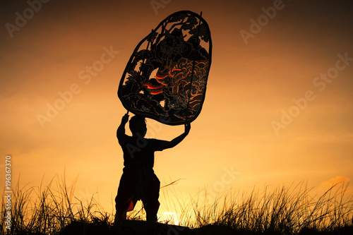 Silhouette man raise Thai shadow angel puppet