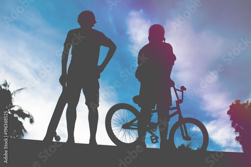 Rear view of two young man bmx bike and skateboard