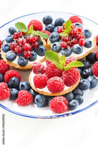 mini cakes with sweet cream and berries on plate  vertical