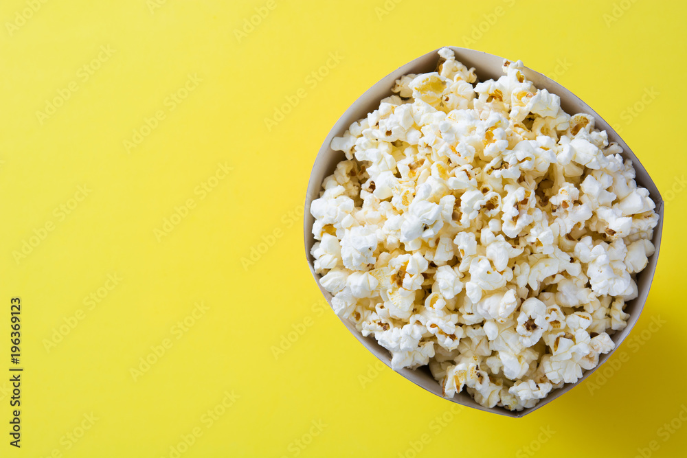Striped box with popcorn on yellow background. Top view.Copyspace Striped box with popcorn on yellow background. Top view.Copyspace