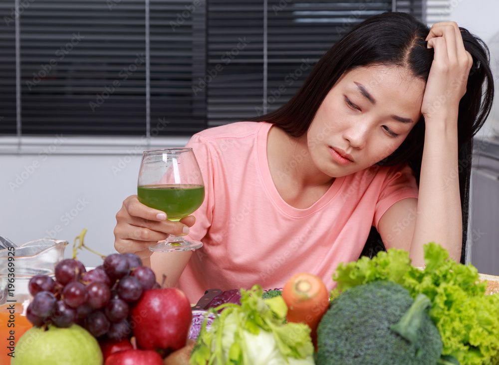 unhappy woman drinking vegetable juice in kitchen unhappy woman drinking vegetable juice in kitchen