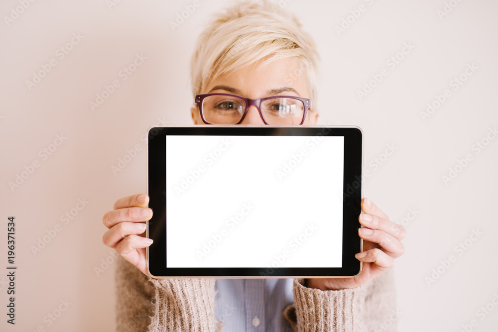 Close up focus view of a tablet in a horizontal position with a white editable screen while a pretty woman holding it.