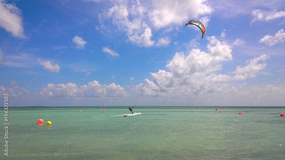 Kitesurfer over a beautiful tropical beach with green palm trees and pacific crystal turquoise water. Cayo Guillermo, Cuba