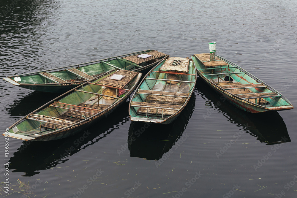 Four empty rowing boats stop over the river at Trang An Grottoes in Ninh Binh, Vietnam. Four empty rowing boats stop over the river at Trang An Grottoes in Ninh Binh, Vietnam.