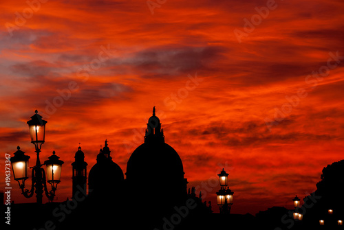 Red blood sky sunset over Venice Lagoon with Salute Basilica domes and old lamps