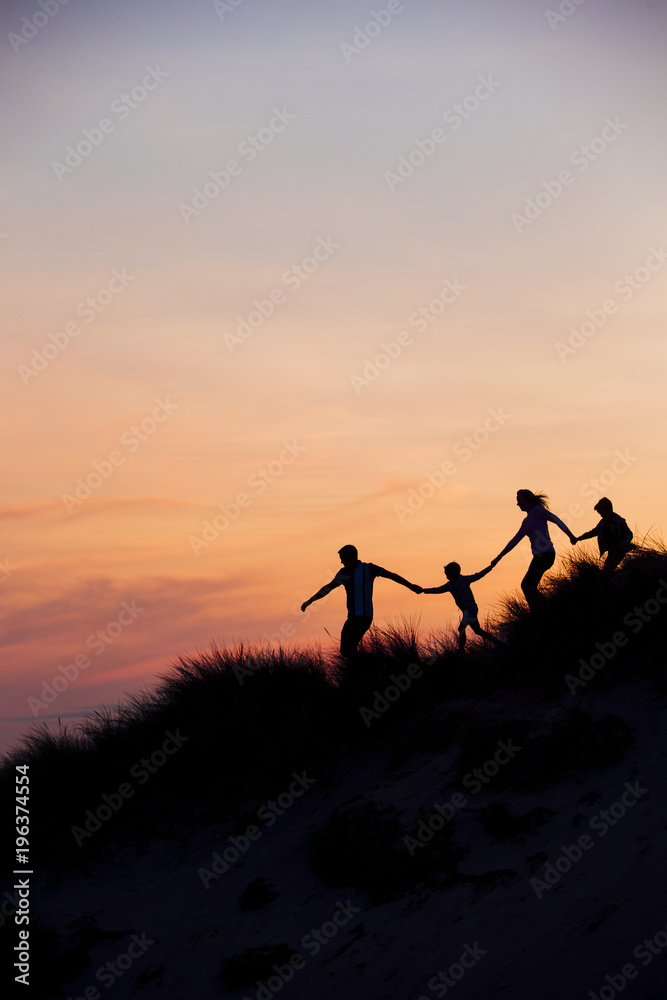 Fototapeta premium Sylwetka rodziny biegnącej przez wydmy