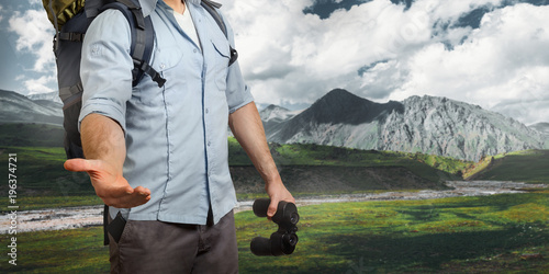 Uunrecognizable Young Traveler Man With A Baclpack And Binoculars, Stretches Out His Hand Mountains. Help In Travel Concept photo