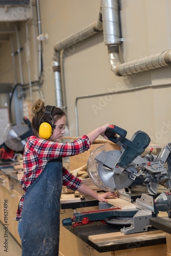 Female carpenter using grinder cutting machine photo