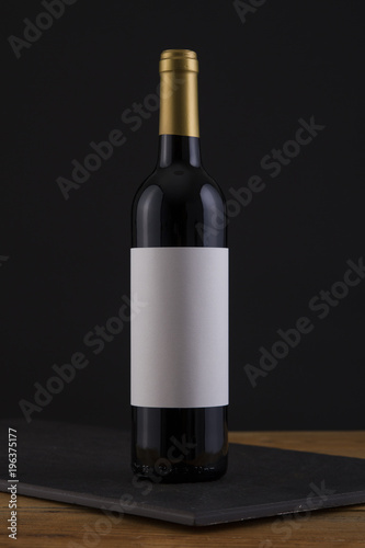 Isolated Red Wine Bottle in a Black, wood Background and White Label