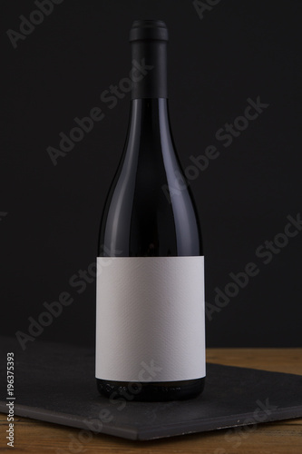 Isolated Red Wine Bottle in a Black, wood Background and White Label