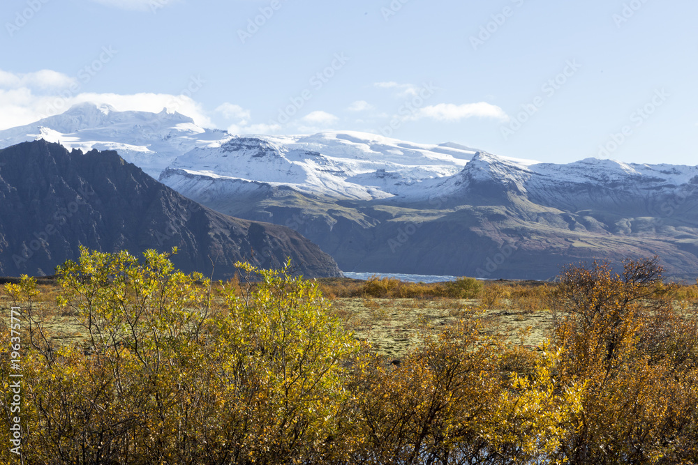 Island im Herbst, im Süden der Insel, leuchtendes Farbspiel, im Hintergrund ein ferner verschneiter Bergzug