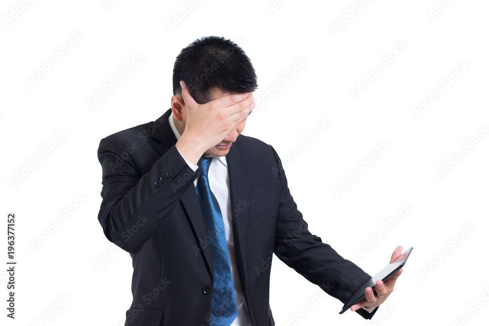 Modern asian businessman hand holding digital tablet suffering from headache on white background. Hiding he face and confused angry with unhappy. sad face and standing and thinking negative Modern asian businessman hand holding digital tablet suffering from headache on white background. Hiding he face and confused angry with unhappy. sad face and standing and thinking negative