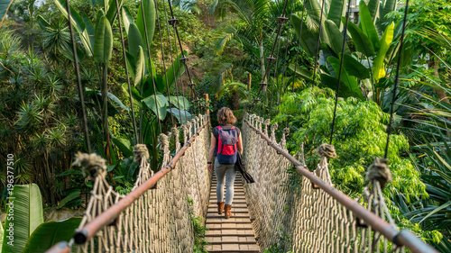 Hübsche Frau auf einer Hängebrücke in tropischem Wald photo