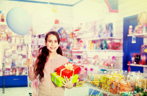Smiling small girl receives boxes with gifts in the toys shop