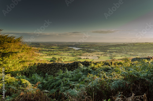 The sun sets over Tittesworth Reservoir and the surrounding fields on the Roaches  Staffordshire in the Peak District National park.