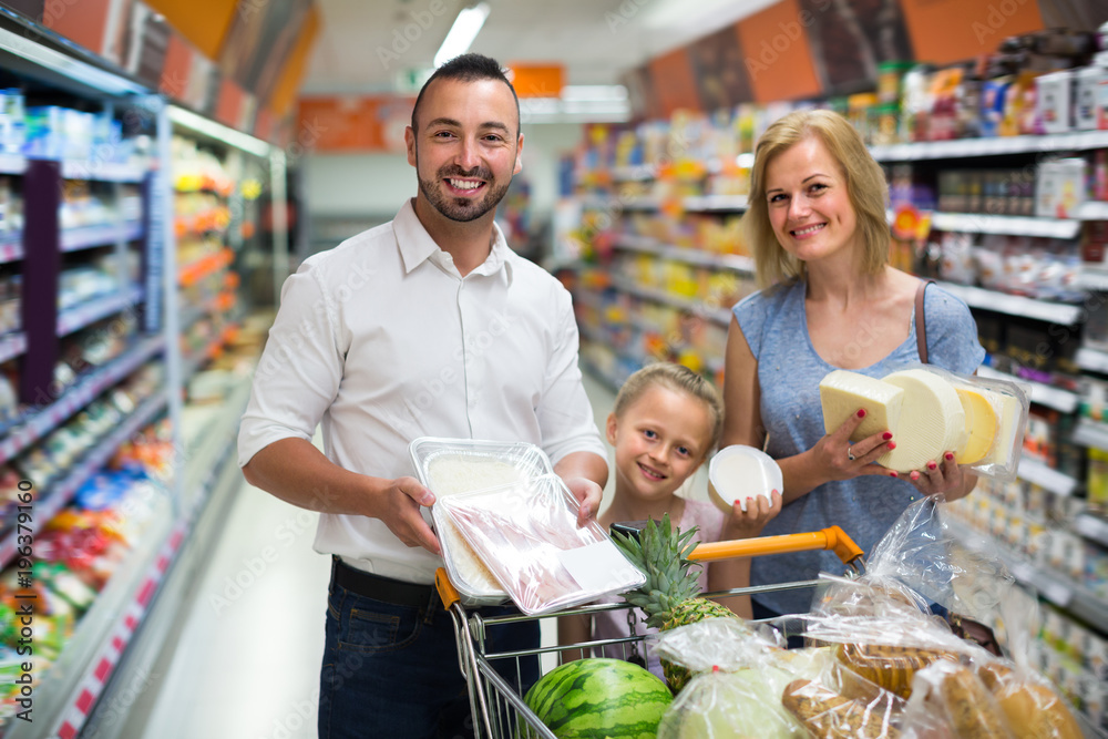 Glad parents with child shopping in hypermarket