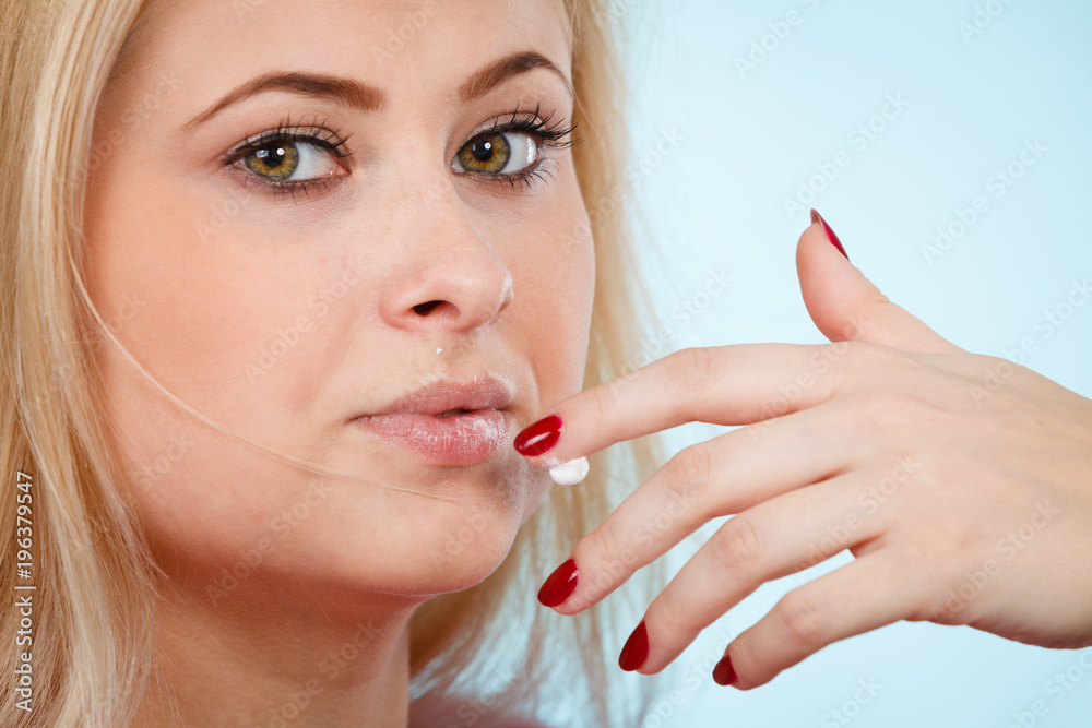 Woman applies lip balm cream to her lips Woman applies lip balm cream to her lips