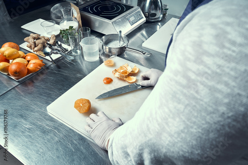 the chef cuts the fruit. A lot of oranges on the table. The cook works in a professional kitchen