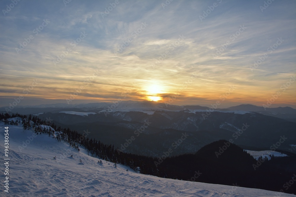 Sunset time in a cloudy day in Ciucas Mountains. The fir forest is covered with snow