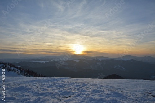 Sunset time in a cloudy day in Ciucas Mountains. The fir forest is covered with snow