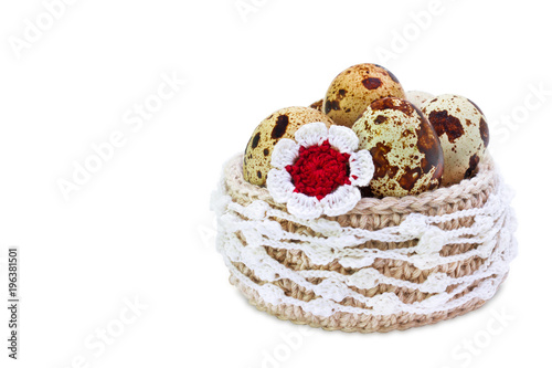 Linen crochet lace basket with Easter quial eggs and crochet colorful flower isolated on white background. The photo of Easter, spring, healthy organic food concept. photo