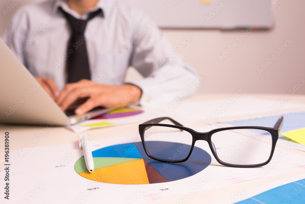 workplace with a laptop, phone, graphics, glasses workplace with a laptop, phone, graphics, glasses