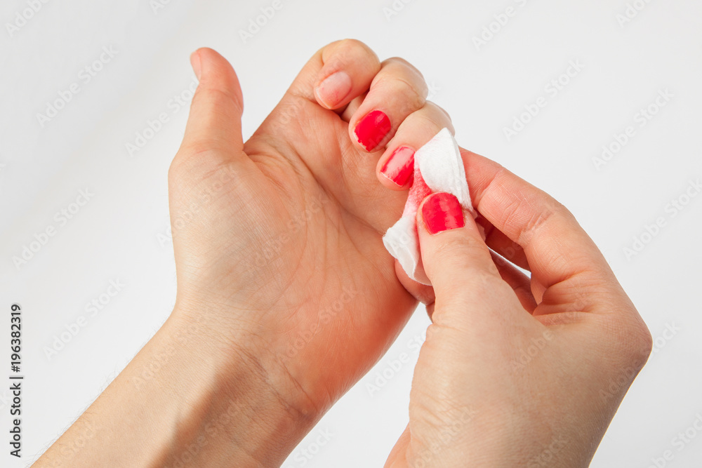 The girl removes the nail polish with cotton wool. Cleaning nails from polish