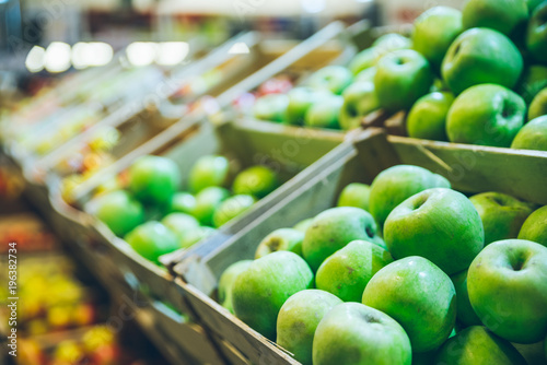 green apples in boxes on market shelves. grocery shopping concept