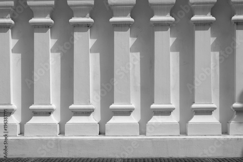 line of low relief sculpture at white concrete wall with shadow.