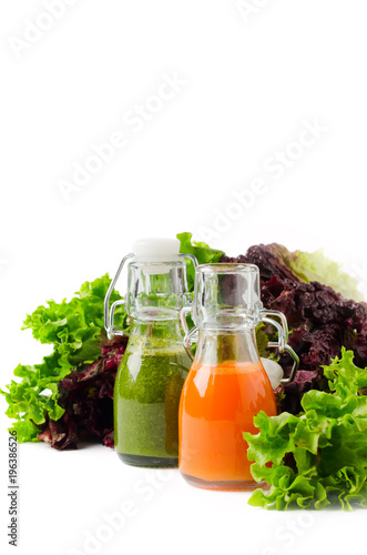 Two bottles of vegetable juices on white