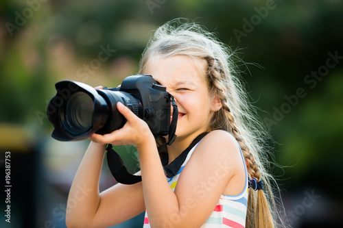 happy female child taking pictures with camera in park