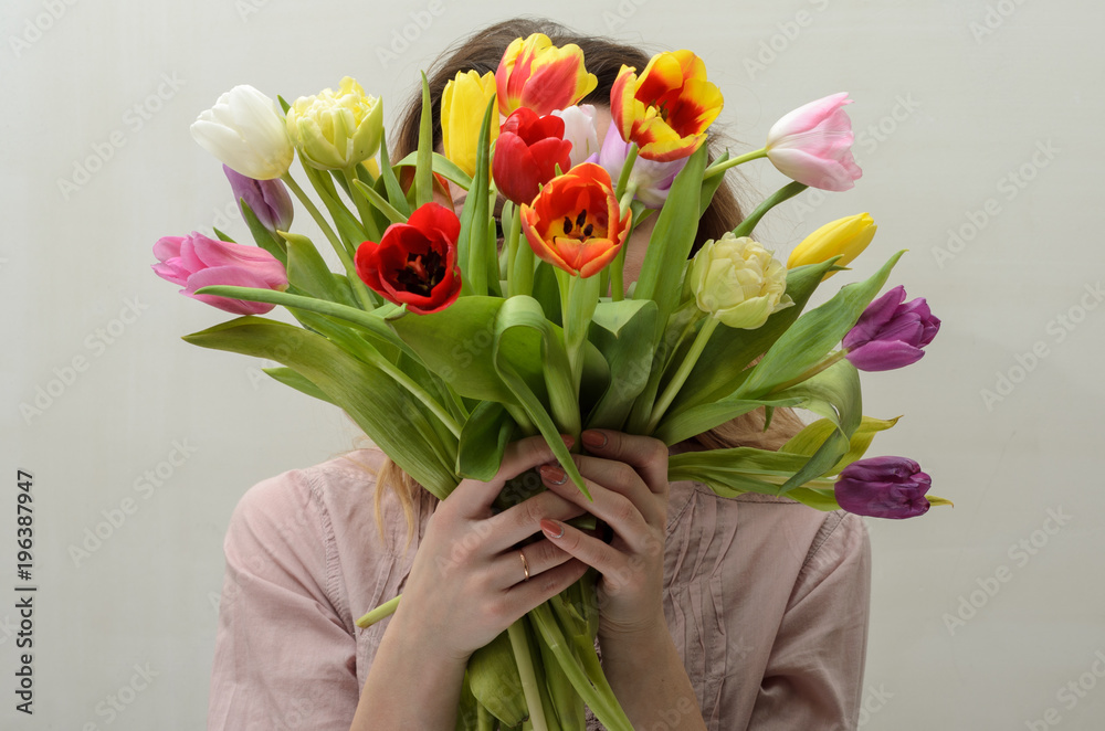 Young charming girl with a bouquet of flowers - multi-colored tulips Young charming girl with a bouquet of flowers - multi-colored tulips