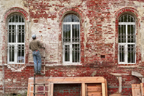Obraz na plátně Working restorer restores the old wall of the building