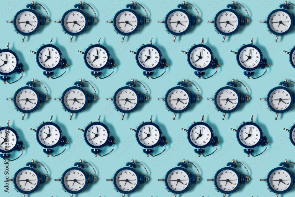 Flat lay retro beautiful new alarm clock on blue color background. Pattern. Top Flat lay retro beautiful new alarm clock on blue color background. Pattern. Top