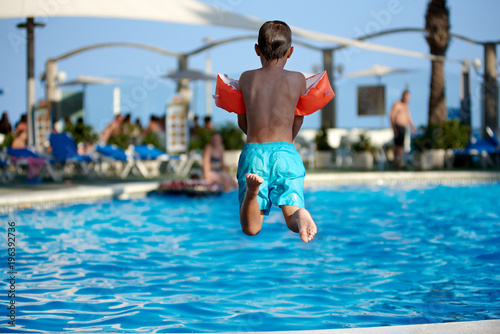 Caucasian boy having fun jumping into the pool. © Artem