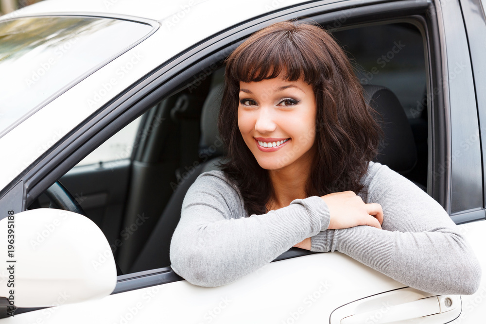 Happy owner of a new car. Young pretty woman driver smiling to you Happy owner of a new car. Young pretty woman driver smiling to you